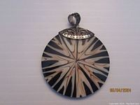 Front of circular black and beige mosaic inlay pendant with silver decorative bail