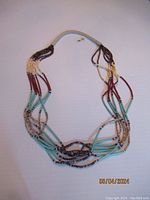 Full necklace laid out flat, showing the curvature and multi-strand design, highlighting the combination of bead materials and colors.