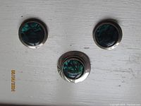 Front view of the pair of round abalone shell stud earrings and matching circular sterling silver brooch with abalone shell inlay and engraved detail.