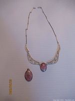 Full view of both Rhodochrosite gemstone pendants; the larger pendant is attached to a sterling silver necklace with decorative filigree sides.