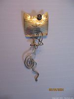 Sterling silver cat brooch shaped like a stylized cat face with wire fashioned wavy tail detail.