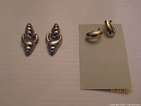 Two sets of earrings: Thai sterling silver on the left, gold tone on the right on a gray earring card.