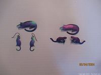 Two sets of titanium cat pins and matching earrings shown together - includes both large pin with hook earrings and smaller curled cat pin with stud earrings