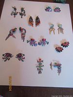 Full lot showing nine pairs of whimsical metal earrings and two pins, all colorful and playful in design, displayed on a white background.