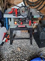 Front view of the Craftsman table saw showing control panel with red knobs and black stand.