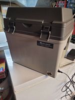 Front side view of the portable electric mini fridge/heater with brown lid and beige body, showing Midland brand label.