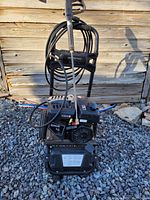 Front view of pressure washer showing engine, frame, hose, and spray gun