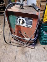 Front view of Lincoln Electric AC-225 arc welder showing amperage dial and power cables coiled around base.