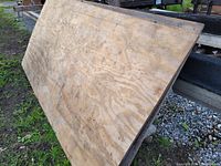 Full view of stacked plywood sheets showing surface texture and discoloration.