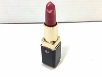 Front angle showing the opened lipstick, pink shade with embossed heart symbol.