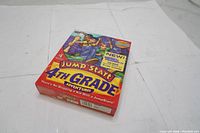 Front cover of Jump Start 4th Grade Adventures PC software showing colorful artwork with cartoon kids and text about learning subjects.