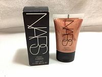 Front view of NARS Illuminator with box and tube showing brand and product details on box and front of tube.