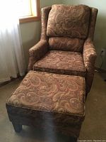Full view of the chair and ottoman side by side showing upholstery and overall condition.