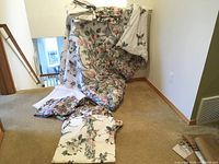 Full view of comforter set including comforter, bed skirt, curtains, and sheets spread and folded on floor against wall.