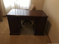 Front view of the wooden desk showing the solid top and panel base structure.