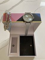 Jessica Carlyle ladies watch with silver mesh band and crystal-accented bezel displayed in watch box along with three silver-toned beaded stretch bracelets.