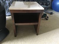 Full front view of wooden night stand showing carved legs, open lower shelf, and polished stone top.