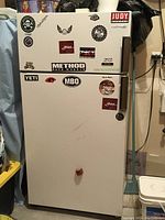 Front view of white refrigerator/freezer with various stickers applied to the doors.