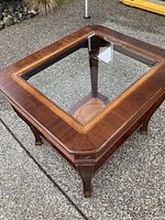 Square wood side table with glass inset top, dark brown finish, curved legs and decorative lower shelf.