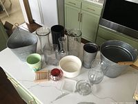 Overhead and angled views of all vases and containers arranged on a white kitchen countertop, showing different materials and types of items.