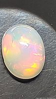 Close-up photo of the oval cabochon Ethiopian opal showing vibrant color flashes and smooth polished surface.