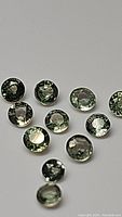 Close-up photo of multiple small natural green sapphires with round cut and clear VS-VVS clarity.