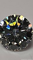 Close-up image showing top view of round brilliant cut moissanite, displaying multi-colored fire and sparkle on facets.