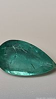 Close-up image showing the pear cut 1.84 carat natural emerald from Colombia with visible inclusions and bright green color.