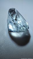 Close-up angled view of aquamarine gemstone showing facets and light blue color, pear shape.
