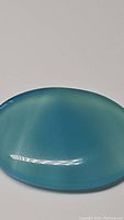 Close-up of oval cabochon icey blue chalcedony showing smooth polished surface and translucent color.