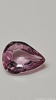 Close-up image of a single pear-shaped pink sapphire gem showing its color, cut, and clarity