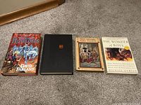 Four books arranged on carpet, showing front covers and varying sizes.