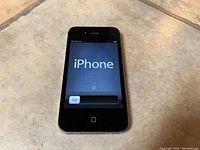 Front view of powered on iPhone 4 displaying welcome screen with slider bar.