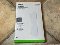 Front view of Belkin UltraGlass 2 screen protector packaging showing the product name, compatibility with iPhone 15 Pro, and key features such as 2.7x strength and ease of application.