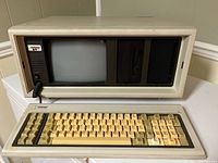 Front view showing CRT screen, keyboard with yellowed keys, floppy disk drive, and Compaq branding