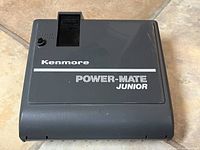 Top front view of the Kenmore Power-Mate Junior vacuum attachment showing the brand and model name.