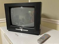 Front angle view of Misakai 13-inch CRT TV with remote control placed next to it, showing the buttons and built-in speakers.