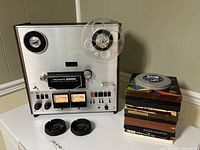 Front view of deck with one reel, adapters and stack of tapes