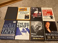 Display of eight political books arranged in two rows on carpeted floor, showing front covers and titles.