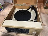 Front angled view of the opened Seabreeze portable record player displaying the turntable, tonearm, and changer mechanism inside a beige woven fabric case.