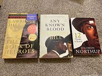 Front cover photo showing three slavery-related books: "The Book of Negroes" and "Any Known Blood" by Lawrence Hill, and "12 Years a Slave" by Solomon Northup.