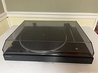 Front view of Sony PS-LX100 turntable with closed dust cover, showing model branding.