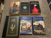 Top-down view of six books laid on carpet: The Children of Húrin, The Silmarillion, The Handmaid's Tale, Jane Eyre, The Odyssey, Great Expectations.