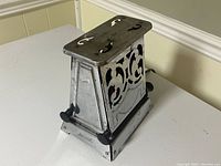 Side angle view showing the toaster's decorative cutout design and overall metal construction.