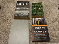 Four war-related books arranged on carpet: Collapse, The Gurkhas, Escape from Camp 14, and a grey-covered book.