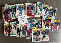 Overview of part of the hockey cards from the lot laid out showing various players in uniform on front.