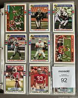 Array of football cards in a binder showing players Tim Brown, Eric Dickerson, Steve Largent, Dan Marino, Jerry Rice, Roger Craig, Ronnie Lott, and more, indicating part of the 1989 Topps football card complete set with 'Record Breaker' and 'Topps All Pro' labels.