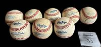 Eight Rawlings International League official baseballs grouped together showing game use marks and dirt.