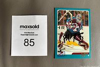 Photo of 2003-04 OPC Patrick Roy hockey card signed in black Sharpie, with MaxSold lot number card beside it.