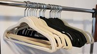 Front and side view of the velvet hangers on a rack showing the mix of beige and black.